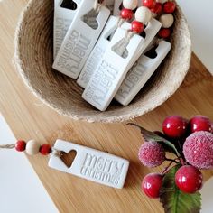 some candy sticks are in a bowl on a wooden tray next to berries and flowers