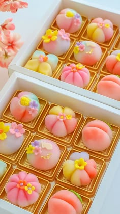 there are many different colored desserts in the box on this table, and one is decorated with flowers