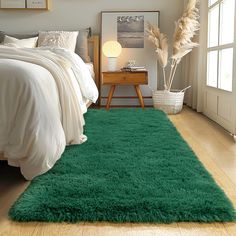 a bed room with a neatly made bed and a green rug on the floor in front of it