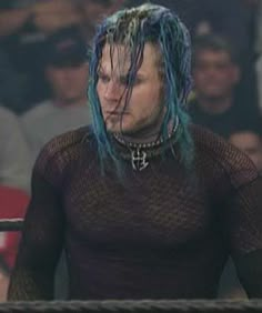 a man with blue hair standing in front of a crowd