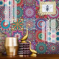 colorful wallpaper with gold vases and other decorative items on a wooden table in front of it