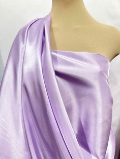 a mannequin wearing a purple dress with one shoulder draped over the other,