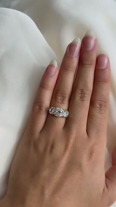 a woman's hand with a diamond ring on top of her left hand, resting on a white sheet