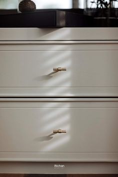 a white dresser with two drawers and a ball of yarn sitting on top of it