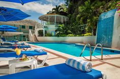 an outdoor swimming pool with lounge chairs and umbrellas