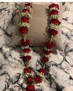 a red rose and baby's breath flower necklace on a pillow with matching beads