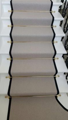 a carpeted stair with black trim and gold hardware on the bottom, along with white stairs