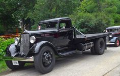 an old black truck is parked on the side of the road