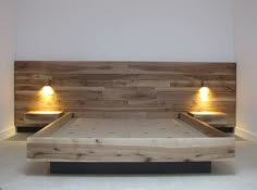 a bed made out of wood with two lights on each side and no headboard