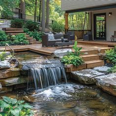 a small waterfall in the middle of a garden with steps leading up to an outdoor living area