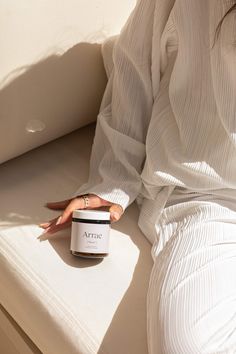 a woman sitting on a couch with her hand resting on the top of a jar