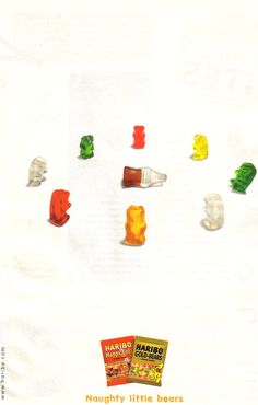 there are many gummy bears on the white paper and one is yellow, green, red, orange