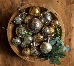 a wooden bowl filled with christmas ornaments on top of a table