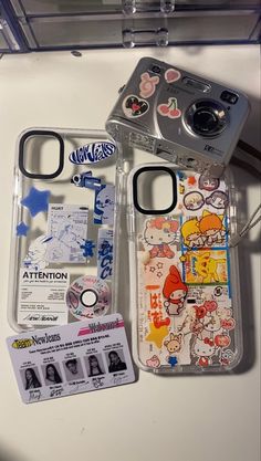 two cell phones sitting next to each other on top of a white table with stickers