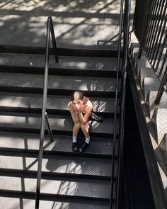 a woman is sitting on the stairs with her legs crossed and looking down at her cell phone