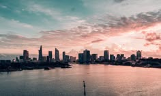 the sun is setting over a large body of water with tall buildings in the background