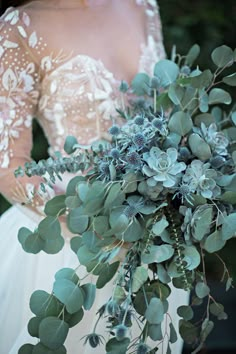 a bride holding a bouquet of flowers and greenery