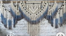 macrame wall hangings with blue and white accents on a brick wall next to flowers