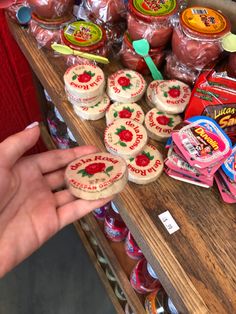 a person is holding up some cookies on a table with other items in the background