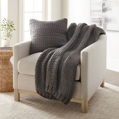 a white chair with a gray blanket on it