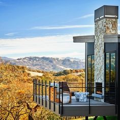 an outdoor deck with furniture and mountains in the background