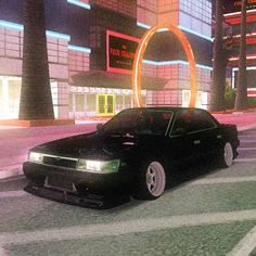 a black car driving down a street next to tall buildings and neon lights at night