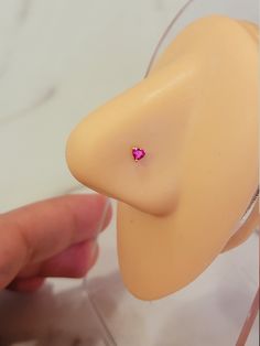 a hand holding a fake nose with a tiny pink diamond in it's mouth