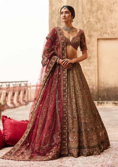 a woman in a red and gold lehenga with her hands on her hips