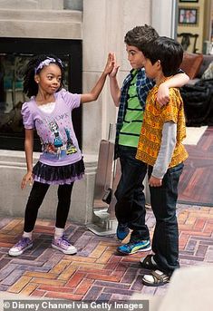 three young children standing in front of a fire place with their hands up to each other