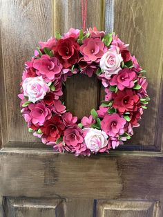 a wreath with pink and white flowers hanging on a door