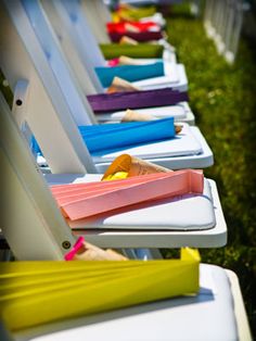 row of white lawn chairs with colorful trays on them