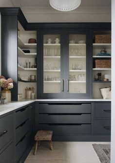 a kitchen with gray cabinets and white counter tops, along with a wooden bench in the center