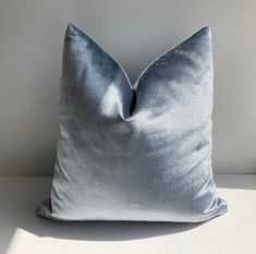 a blue velvet pillow sitting on top of a white table next to a lamp shade