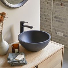 a bathroom sink sitting on top of a wooden counter next to a vase with flowers