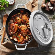 a pan filled with chicken and mushrooms on top of a wooden table