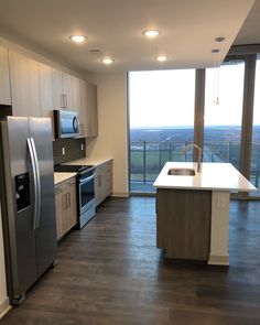 an empty kitchen with stainless steel appliances and large windows