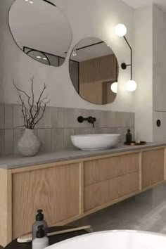 a bathroom with two round mirrors above the sinks and a large tub in front of it