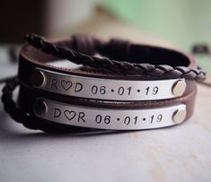 three personalized leather bracelets with metal beads and engraving on the ends, sitting on a table