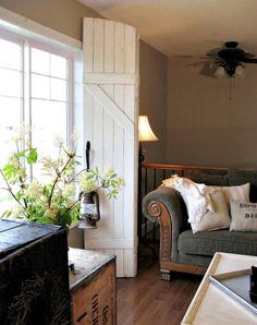 a living room filled with furniture next to a wooden table and white shuttered windows