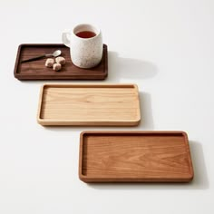 three wooden trays with different types of food on them, one is empty and the other has a cup of tea in it