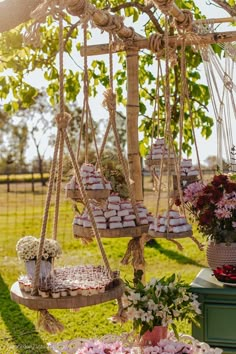 an outdoor dessert table with macaroons and cupcakes hanging from the ceiling