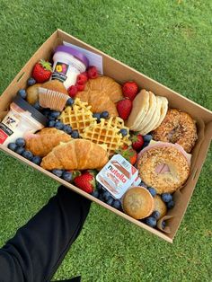 a box filled with assorted pastries on top of a green grass covered field