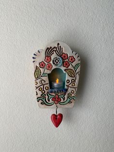 a clock with a candle in the middle and a heart hanging from it's side