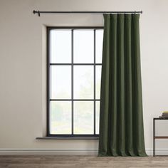 a green curtain hanging in front of a window with a white wall and wooden floor