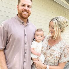 a man and woman standing next to each other holding a baby