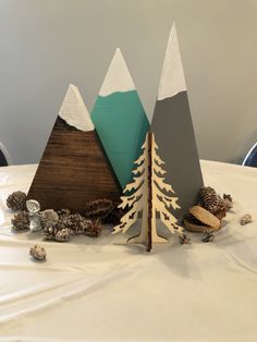 three paper trees on top of a table with pine cones and other decorations around them