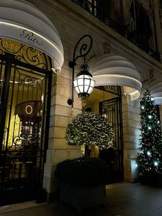 a christmas tree in front of a building with lights and decorations on the outside wall