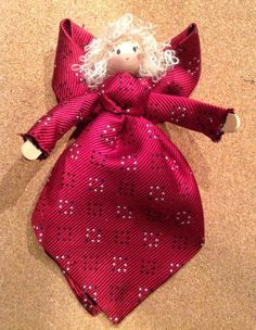 a red cloth doll with white hair wearing a pink bow tie on top of carpet