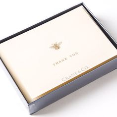 an open box with a bee on the inside and thank you written in gold lettering