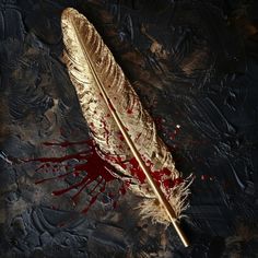 a golden feather with blood splatters on it sitting on top of a black surface